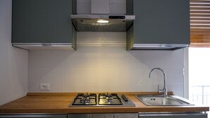 Moderni keittiö, jossa on kaasuliesi, ruostumattomasta teräksestä valmistettu pesuallas ja puinen työtaso.