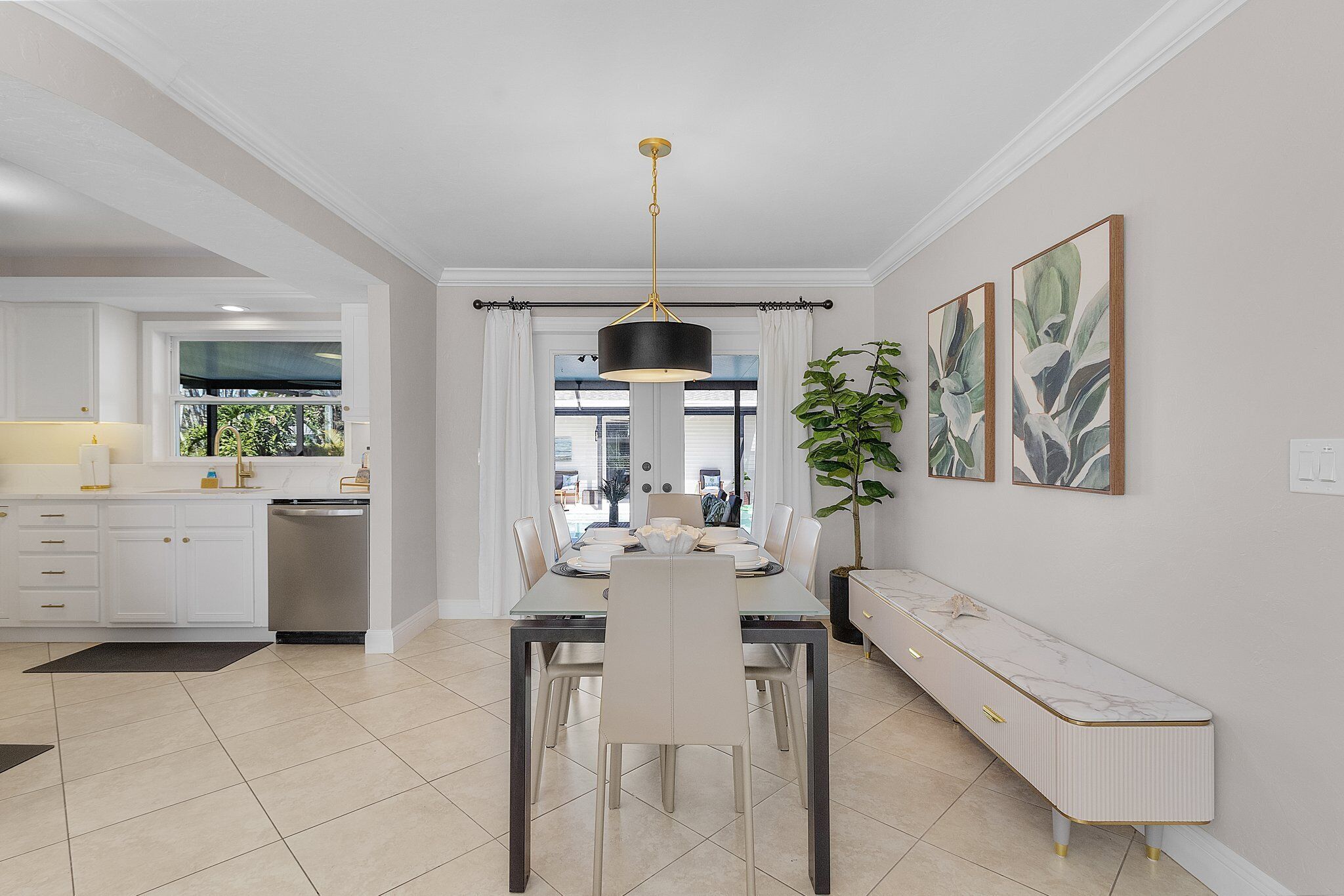 Een moderne keuken met witte kasten, een eethoek met een glazen tafel en een bank langs de muur.