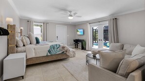 A spacious bedroom with a bed, a sofa, a desk, and a TV.