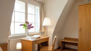 A room with a desk, chair, lamp, and a radiator. - Klosterhotel Lehnin (Kloster Lehnin)