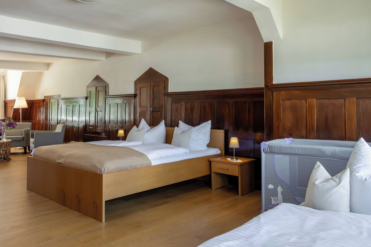 Une chambre spacieuse avec un grand lit, une tête de lit en bois, des tables de chevet avec des lampes et une armoire.