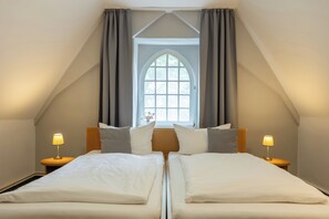 A twin bed room with a large arched window, two bedside tables with lamps, and a wooden headboard. - Klosterhotel Lehnin (Kloster Lehnin)