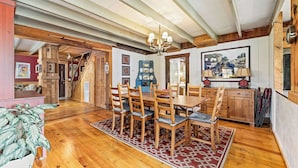 A spacious dining area with wooden furniture, a chandelier, and a patterned rug. - Spacious Rural Farmhouse Getaway with Peaceful Views (Williamsville)