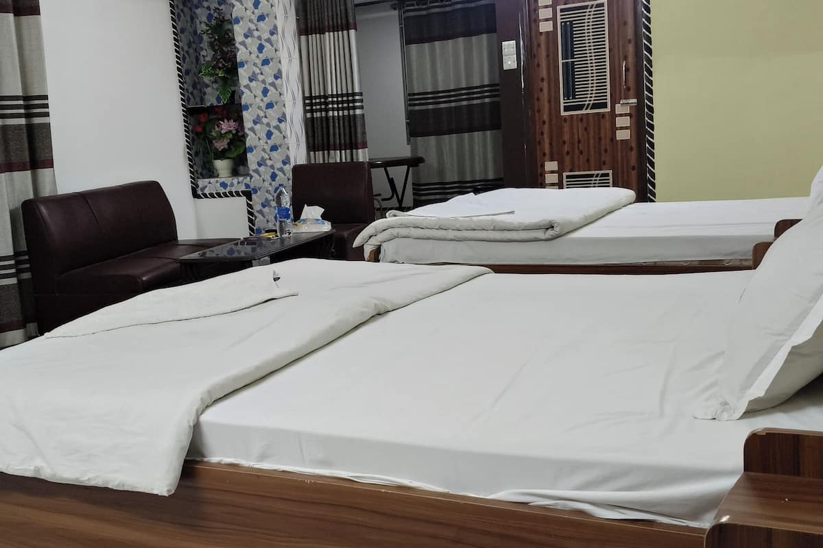 Habitación de hotel con dos camas, un escritorio, una silla y una ventana con cortinas.