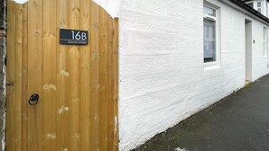 A white house with a wooden gate labeled "16B David Street". - Beautifully Presented, Cosy Town Centre Cottage - Pass the Keys (Dumfries)