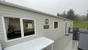 A mobile home with a covered deck, a bench, and a sign that reads "Coworth." - Cosy 3BR Getaway in Beautiful Country Park - Pass the Keys (Beattock)