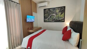 Ein Hotelzimmer mit Bett, Fernseher, Klimaanlage und einem Gemälde an der Wand.