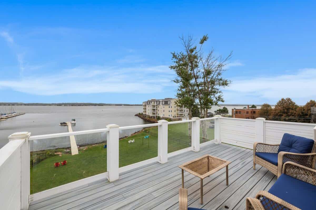 Une terrasse dotée de meubles en osier et offrant une vue sur un plan d’eau.