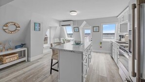 Una cocina moderna con una isla grande, armarios blancos y vistas al exterior.