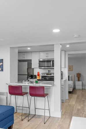 Una cocina moderna con electrodomésticos de acero inoxidable, una isla central con taburetes de bar y una cafetera a la vista.