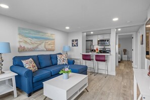 Ein modernes Wohnzimmer mit einem blauen Sofa, einem Couchtisch und einem Gemälde an der Wand.
