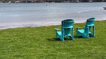 A grassy area with two chairs facing a body of water.