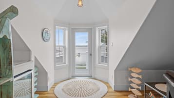 Une pièce avec vue sur la mer, un tapis rond et un objet décoratif en forme de poisson en bois.
