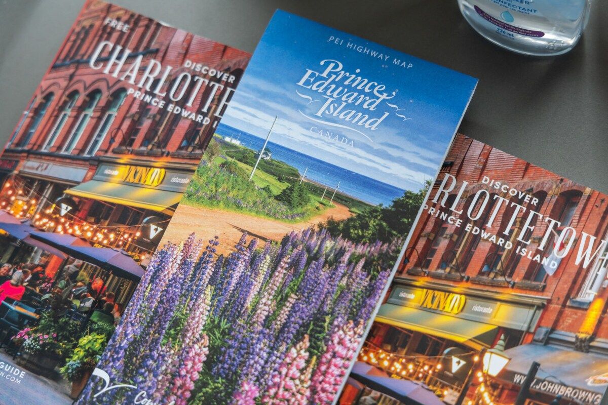 Un libro guía de viajes titulado 'Discover Prince Edward Island' con un mapa y una vista de una calle con edificios y flores.