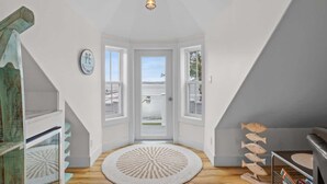 A spacious room with a large window, a round woven rug, and a wooden fish decoration.