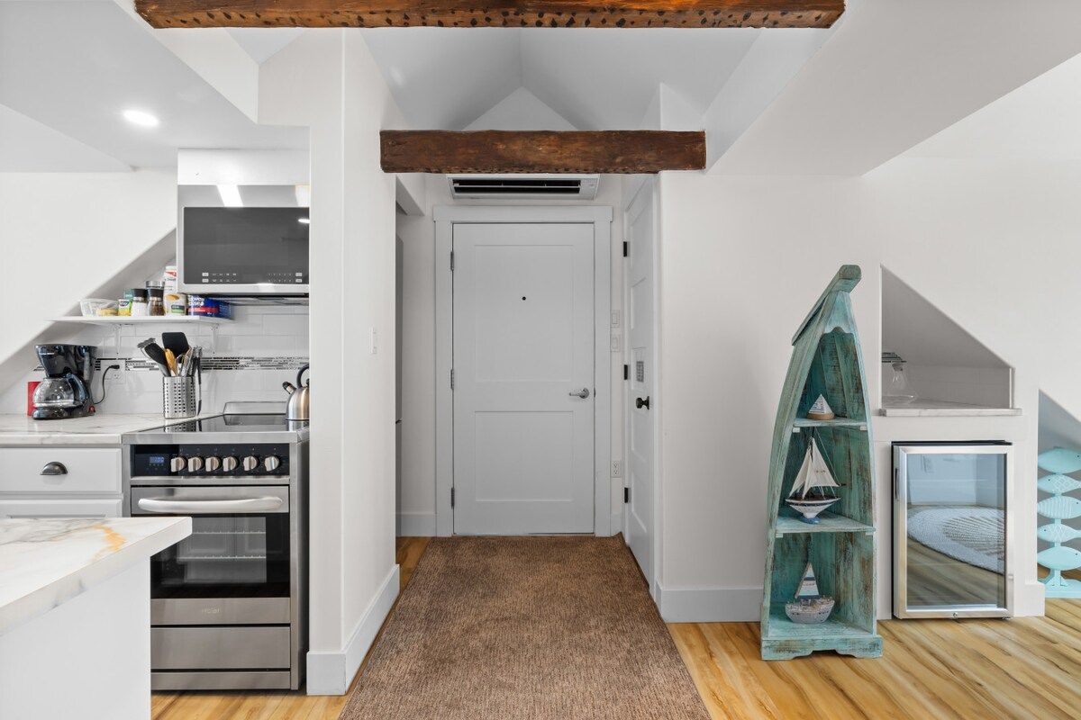 A compact kitchen with a built-in oven, a microwave, and a coffee machine.