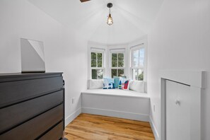 Ein Zimmer mit Erkerfenster, einem dunklen Holzschrank und einer weißen Wand.