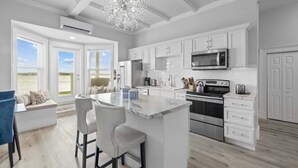 A modern kitchen with white cabinetry, a central island, and a large chandelier.