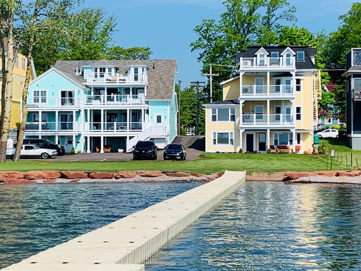 Une propriété située au bord de l’eau, avec des immeubles à plusieurs étages, une piscine et des voitures garées.