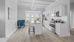 A modern kitchen with white cabinetry, a central island, and a view to the outdoors.