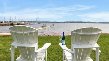 Dos sillas Adirondack blancas mirando un puerto deportivo con barcos y una superficie acuática tranquila.