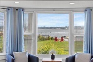 A room with a view of a body of water, a lawn, and two red chairs. - Waterfront Posh King Studio Suite Downtown Ch'town (Charlottetown)
