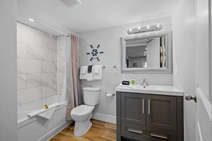 A modern bathroom with a shower, toilet, vanity, and a large mirror. - Waterfront Deluxe King Suite Condo Downtown Chtown (Charlottetown)