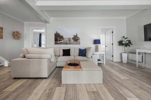 Una sala de estar moderna con un sofá seccional, una mesa de centro y un cuadro de una escena junto al lago.