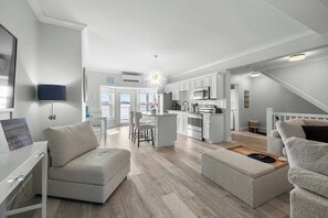 A modern living room with a sofa, ottoman, and a dining area with chairs. - Beautiful Waterfront 2 Bdrm Condo Downtown Ch'town (Charlottetown)