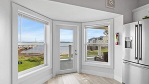 A modern kitchen with a large white refrigerator, a view of a waterfront, and a door leading to an outdoor area. - Beautiful Waterfront 2 Bdrm Condo Downtown Ch'town (Charlottetown)