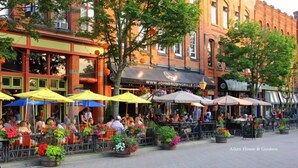 An outdoor seating area with tables and chairs, surrounded by potted plants and umbrellas. - Beautiful Waterfront 2 Bdrm Condo Downtown Ch'town (Charlottetown)