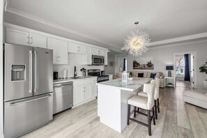 A modern kitchen with white cabinetry, stainless steel appliances, and a central island with bar stools. - Beautiful Waterfront 2 Bdrm Condo Downtown Ch'town (Charlottetown)