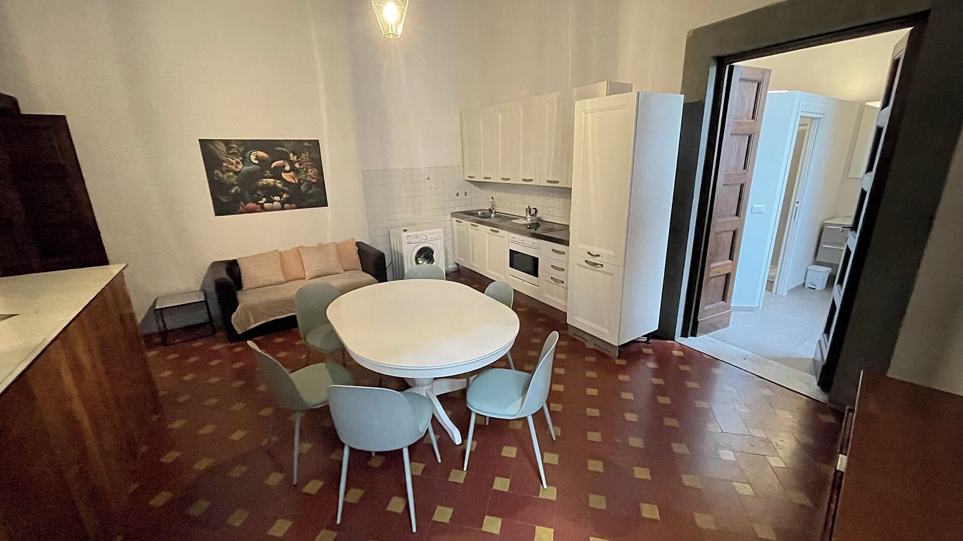 Une cuisine compacte comprenant un coin repas, un canapé et un lave-linge.