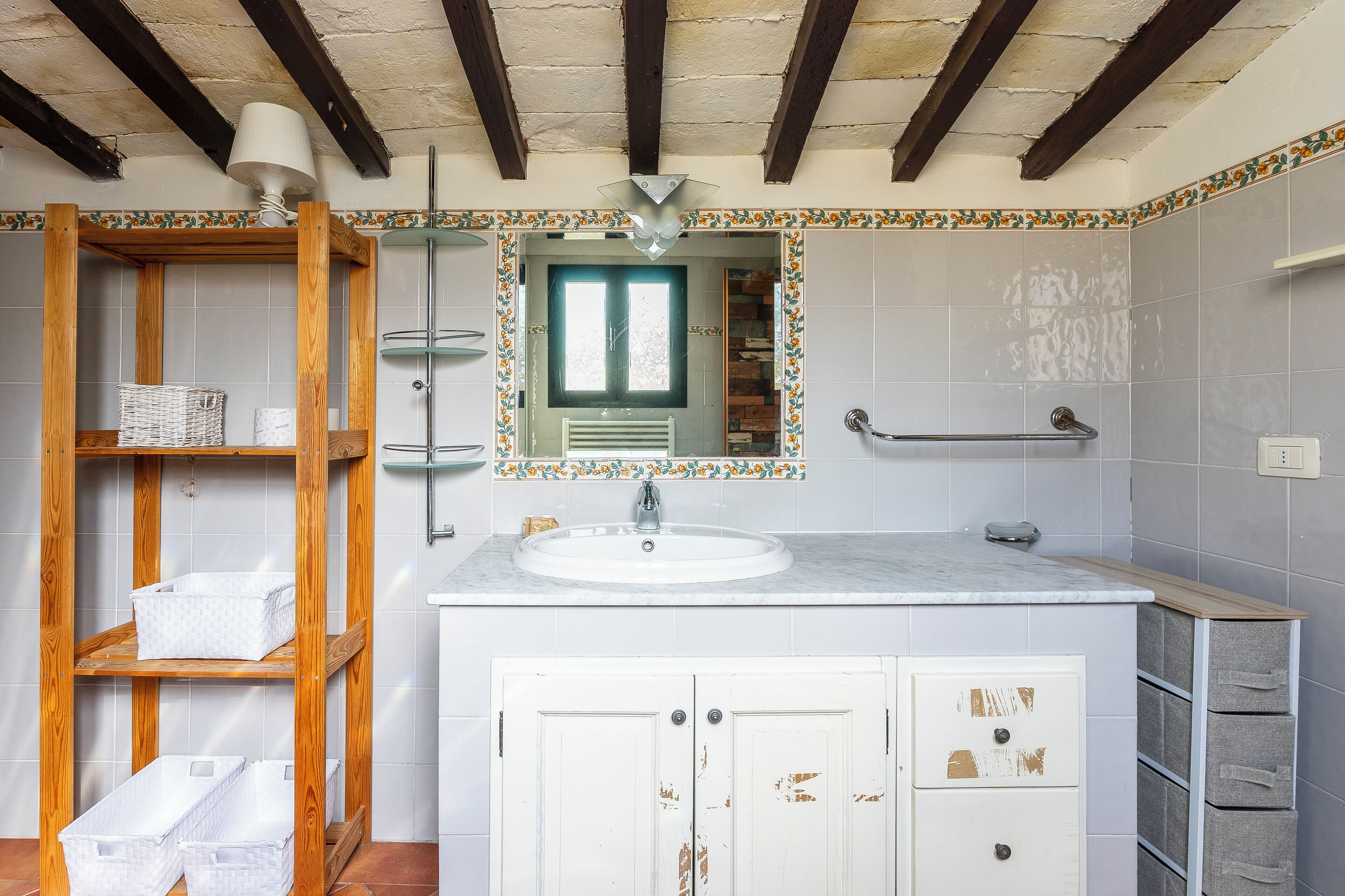 A bathroom with a wooden shelf, a sink, and a mirror.