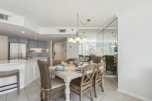 A modern kitchen with a central island, stainless steel appliances, and a dining area with a wooden table and chairs.