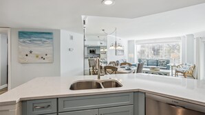 A modern kitchen with a large island, grey cabinets, and a Bosch dishwasher.