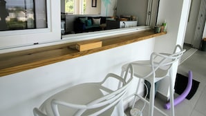 Une cuisine moderne avec des meubles blancs, un plan de travail en bois et un four encastré.