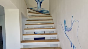 Un escalier avec des marches en bois et une fresque murale représentant la queue d’une baleine.