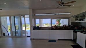Une cuisine spacieuse avec vue sur l’océan, un ventilateur de plafond et une porte-fenêtre coulissante donnant sur un balcon.