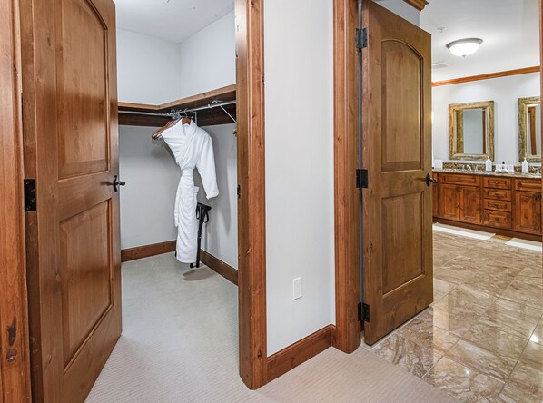 A walk-in closet with a wooden door, a hanging rack, and a white robe. - Spectacular Ritz Carlton Penthouse Residence in Vail. Two levels!! (Vail)