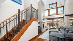 A spacious living area with a wooden staircase, a gray sectional sofa, and a fireplace. - Spectacular Ritz Carlton Penthouse Residence in Vail. Two levels!! (Vail)