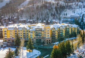 A multi-story hotel with a central courtyard, surrounded by snow-covered trees and a mountainous backdrop. - Spectacular Ritz Carlton Penthouse Residence in Vail. Two levels!! (Vail)