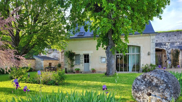 A traditional stone building with a large tree in the foreground, a well-maintained garden with various plants, and a clear view of the building's entrance. - Le Plessis-Lepage "L'Atelier" **** Calm-Space-Green at Azay-le-Rideau (Azay-le-Rideau)
