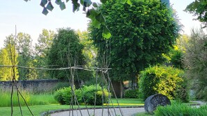 A garden with a circular gravel path, a wooden trellis structure, and various plants. - Le Plessis-Lepage "L'Atelier" **** Calm-Space-Green at Azay-le-Rideau (Azay-le-Rideau)