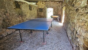 Een tafeltennistafel in een kamer met stenen muren en een rustieke, historische sfeer.