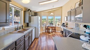 A modern kitchen with a central island, large windows, and a dining area. - River Road Retreat! Hot Tub +  Barndominium (Templeton)