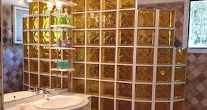 Une salle de bain avec un grand miroir, un lavabo et une douche à parois de verre.