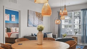 Una sala de estar moderna con una mesa redonda de madera, sillas de mimbre e iluminación colgante de mimbre.