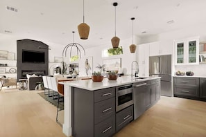 Una cocina moderna con una isla central, electrodomésticos integrados e iluminación colgante.