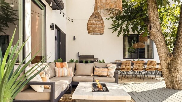 Un espacio al aire libre moderno con sofás, sillas y una chimenea.